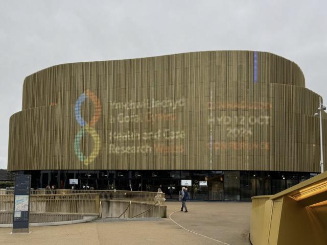 Image of the outside of the Arena Wales showing the Health and Care Research Wales branding and conference information 2023